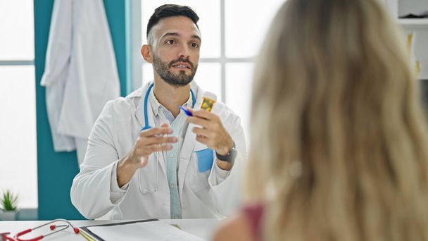 若いヒスパニック男性医師が診療所で錠剤治療を処方する医療相談を受ける - 写真・画像