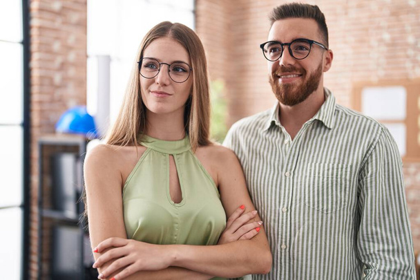 Чоловік і жінка бізнесмени посміхаються впевнено стоячи з обіймами перетнули жест в офісі
 - Фото, зображення
