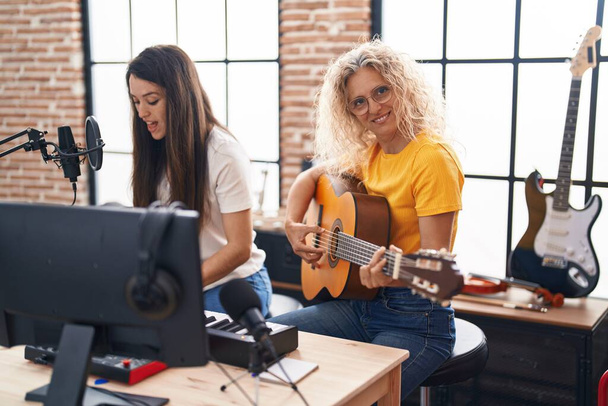 Twee vrouwelijke muzikanten zingen lied spelen klassieke gitaar en piano in de muziekstudio - Foto, afbeelding