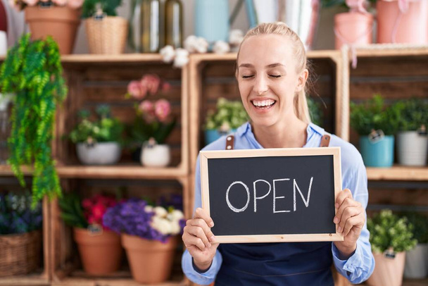 Young caucasian woman working at florist holding open sign smiling and laughing hard out loud because funny crazy joke.  - Photo, Image