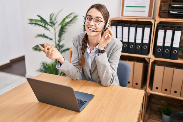 Giovane donna caucasica call center agente sorridente fiducioso parlando in ufficio - Foto, immagini