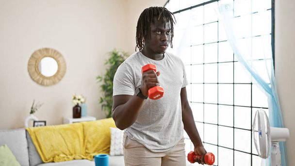 Afrykański Amerykanin używa hantli treningowych w domu - Zdjęcie, obraz