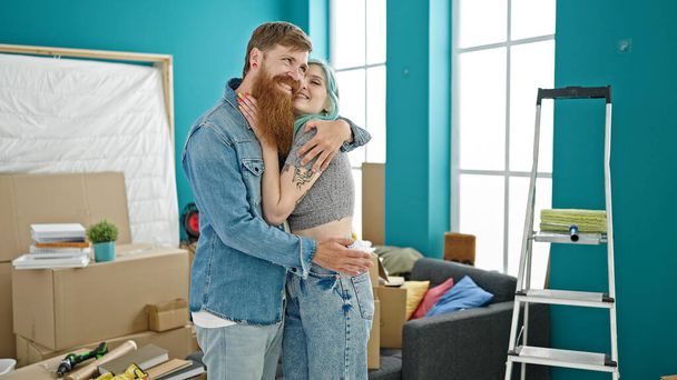 Hombre y mujer pareja abrazándose unos a otros sonriendo en un nuevo hogar - Foto, imagen