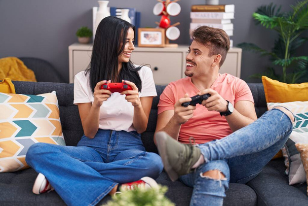 Man and woman couple playing video game sitting on sofa at home - Foto, Imagem