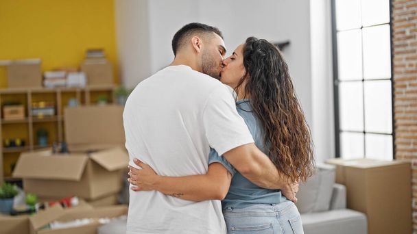 Mann und Frau umarmen sich und schauen sich küssend im neuen Zuhause um - Foto, Bild