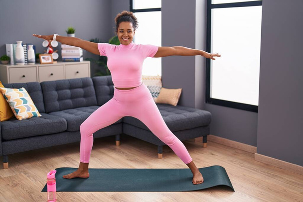 Donna afroamericana sorridente fiducioso yoga di formazione a casa - Foto, immagini