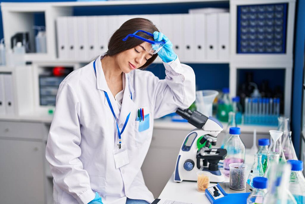 Jonge mooie Spaanse vrouw wetenschapper benadrukt werken in het laboratorium - Foto, afbeelding