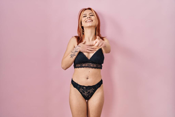 Young caucasian woman wearing lingerie over pink background laughing at you, pointing finger to the camera with hand over body, shame expression  - Photo, Image