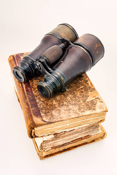 Stare skórzane zeszyty, starożytne notatki zwieńczone zeszłoroczną lornetką przedstawiającą poszukiwaczy przygód i podróże. Przedmioty izolowane na białym - Zdjęcie, obraz