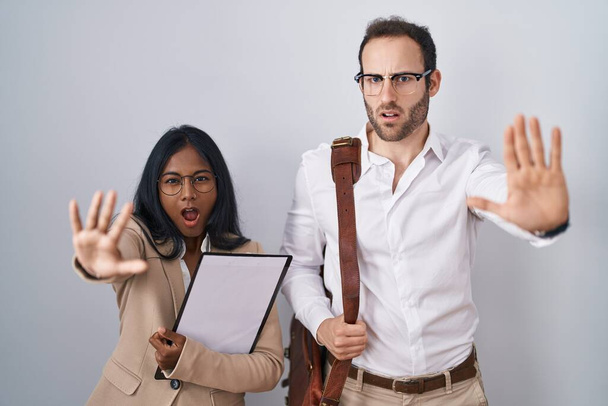 Couple d'affaires interracial portant des lunettes faisant geste d'arrêt avec les mains paumes de la main, expression de colère et de frustration  - Photo, image