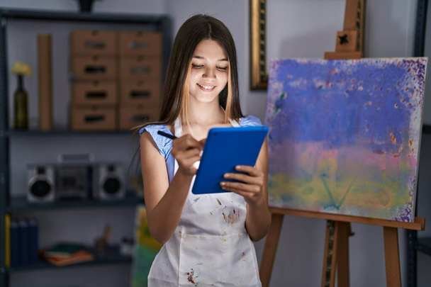 Adorable girl artist using touchpad drawing at art studio - 写真・画像