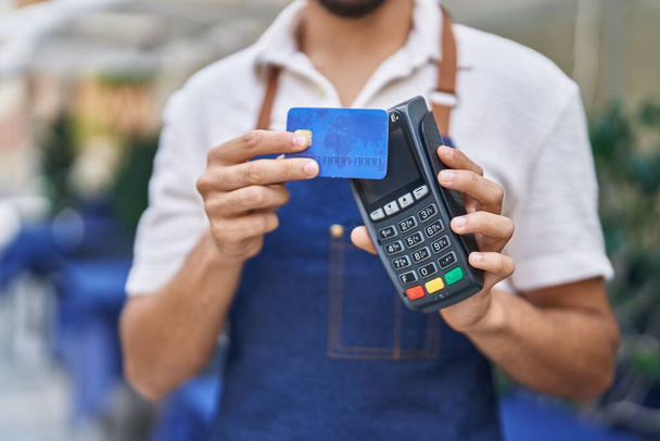 Νεαρός σερβιτόρος Άραβας που χρησιμοποιεί τηλέφωνο δεδομένων και πιστωτική κάρτα στο εστιατόριο - Φωτογραφία, εικόνα