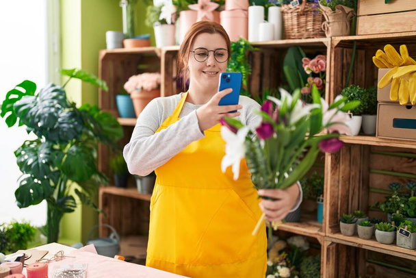 Young beautiful plus size woman florist make photo to bouquet of flowers by smartphone at flower shop - Photo, Image