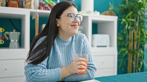 Young hispanic woman drinking juice at dinning room - Photo, Image