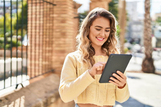 Junge Frau lächelt selbstbewusst mit Touchpad auf der Straße - Foto, Bild