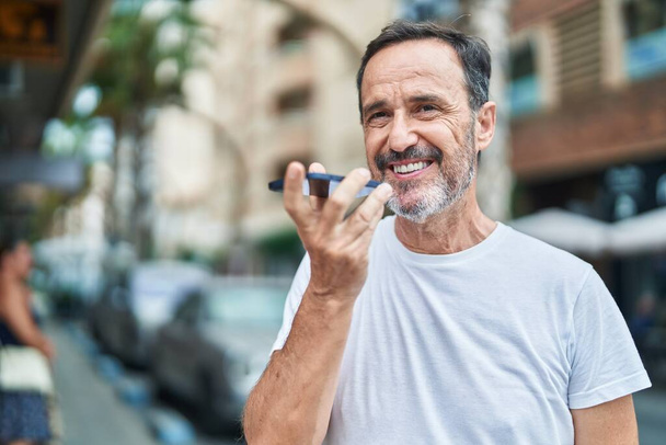 Moyen Age homme souriant confiant parler sur le smartphone à la rue - Photo, image