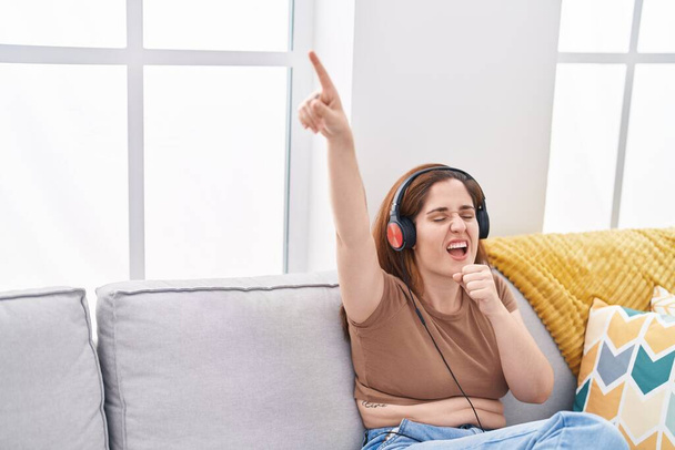 Junge Frau hört zu Hause Musik und singt - Foto, Bild