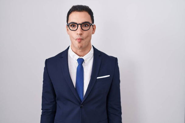 Young hispanic man wearing suit and tie making fish face with lips, crazy and comical gesture. funny expression.  - Photo, Image