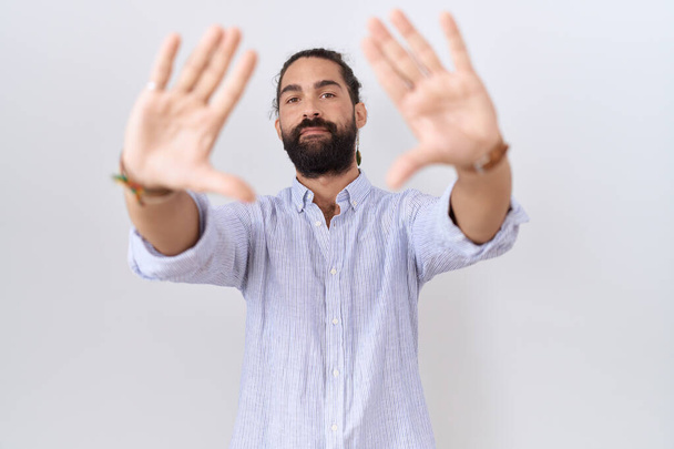 Homem hispânico com barba vestindo camisa casual fazendo quadro usando mãos palmas e dedos, perspectiva da câmera  - Foto, Imagem