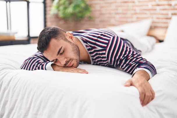jonge latino man liggend op bed slapen in slaapkamer - Foto, afbeelding
