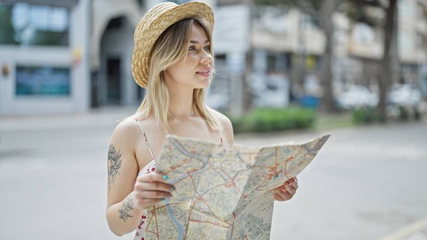 Junge blonde Touristin sieht Stadtplan lächelnd auf Straße - Foto, Bild