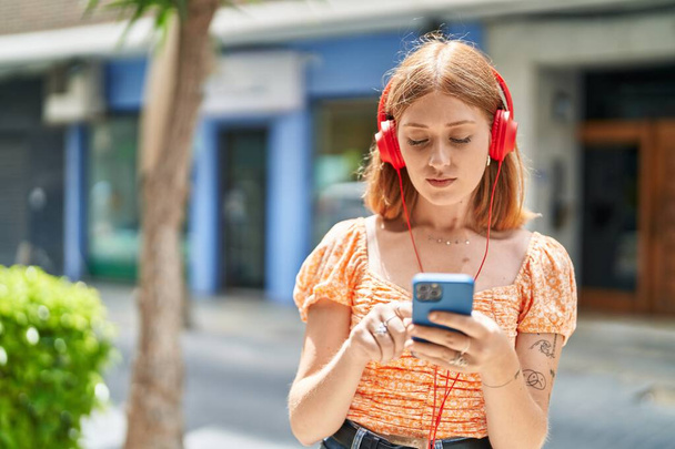 Joven pelirroja escuchando música en la calle - Foto, Imagen