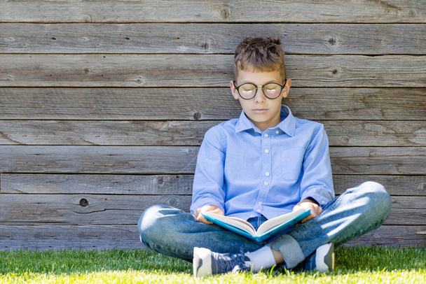 Хлопчик читає книжку на трав'янистому полі. Плоский простір для копіювання
 - Фото, зображення