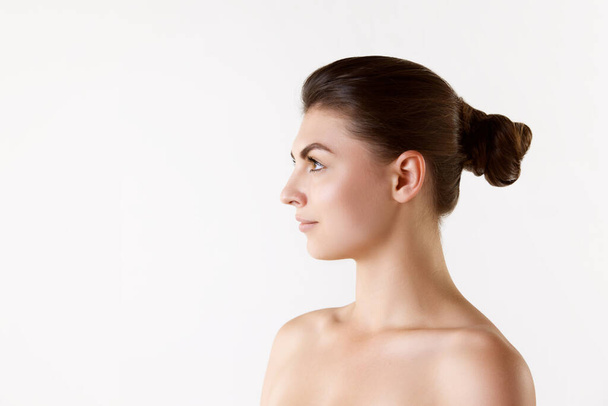Side view image of young beautiful woman with bare shoulders against white studio background. Face shape. Concept of female beauty, skin care, cosmetology and cosmetics, health, ad - Foto, Imagen