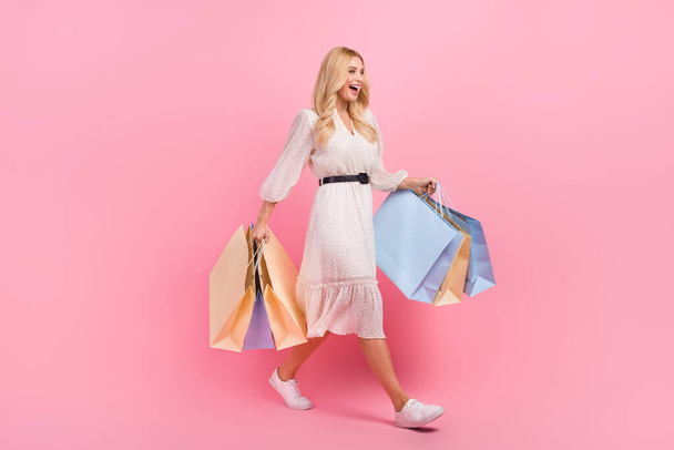 Full body photo of laughing positive mature woman fashionista brand designer choose best quality clothes isolated on pink color background. - 写真・画像