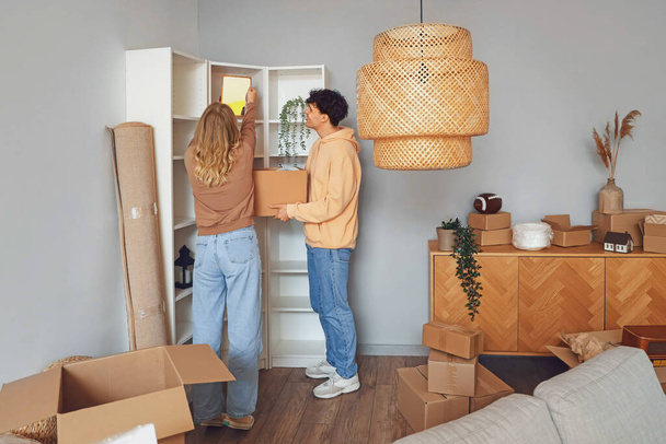 Young couple packing mirror in room on moving day - Photo, Image