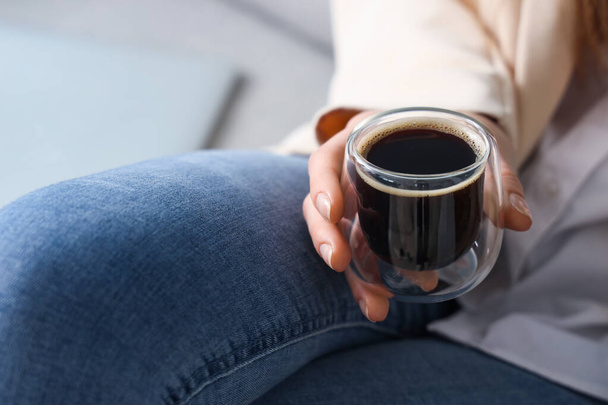 Vrouw zittend op de bank met een glas heerlijke koffie - Foto, afbeelding