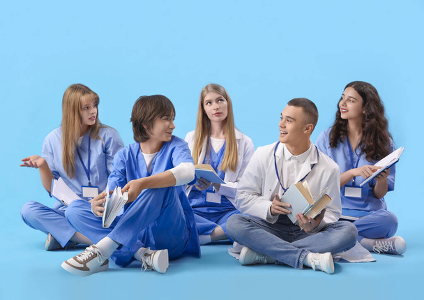 Ομάδα φοιτητών ιατρικής που διαβάζουν βιβλία σε μπλε φόντο - Φωτογραφία, εικόνα