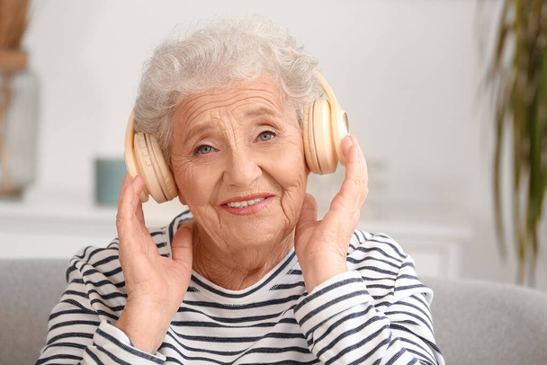 Oudere vrouw in hoofdtelefoon thuis, close-up - Foto, afbeelding