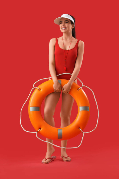 Rettungsschwimmerin mit Ringboje auf rotem Hintergrund - Foto, Bild