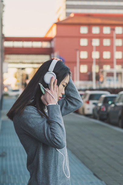 Menina chinesa bonita nova com fones de ouvido
 - Foto, Imagem