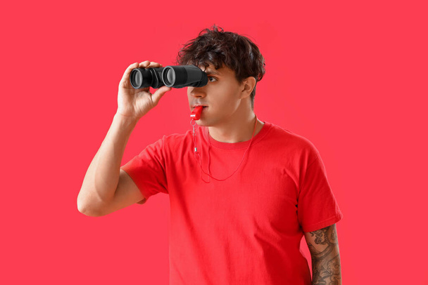 Urospuolinen hengenpelastaja, jolla on kiikarit punaisella taustalla - Valokuva, kuva