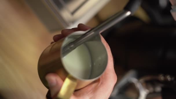 Lähikuva laukaus barista kirnuaminen maitoa kahvi latte ammatillinen kahvinkeitin. Pystysuora video - Materiaali, video