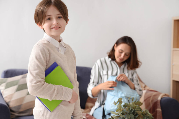 Mother helping her little son to pack schoolbag in living room - Photo, image