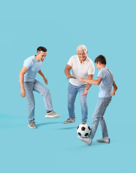 Kleiner Junge mit seinem Vater und Großvater beim Fußballspielen auf blauem Hintergrund - Foto, Bild