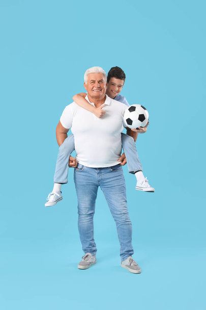 Malý chlapec se svým dědečkem a fotbalový míč na modrém pozadí - Fotografie, Obrázek