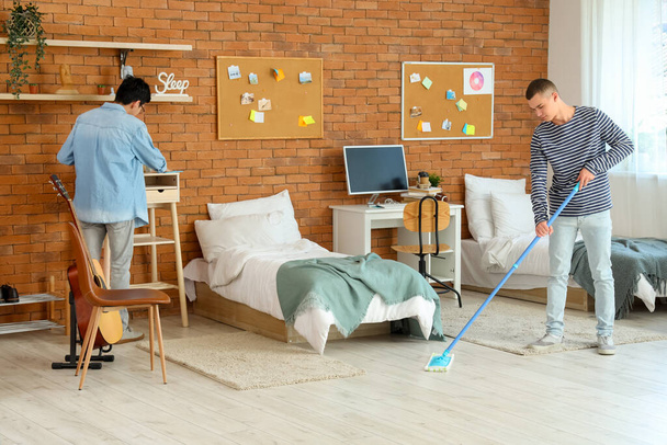 Estudiantes masculinos limpiando en dormitorio - Foto, imagen