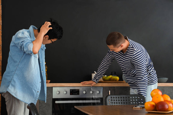 Yurt mutfağında fırın kullanan kafası karışmış erkek öğrenciler. - Fotoğraf, Görsel