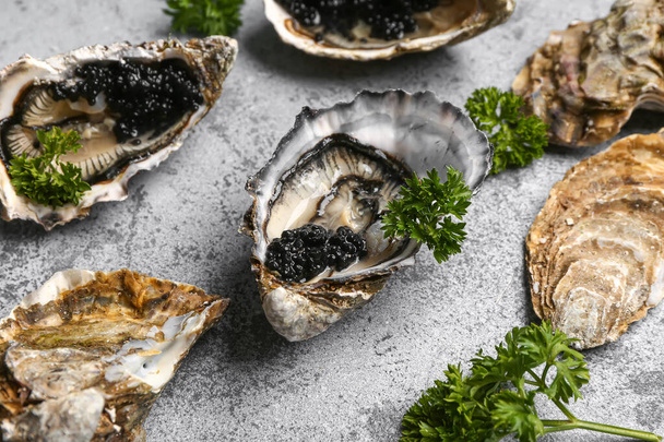 Lekkere oesters met zwarte kaviaar op grijze achtergrond - Foto, afbeelding