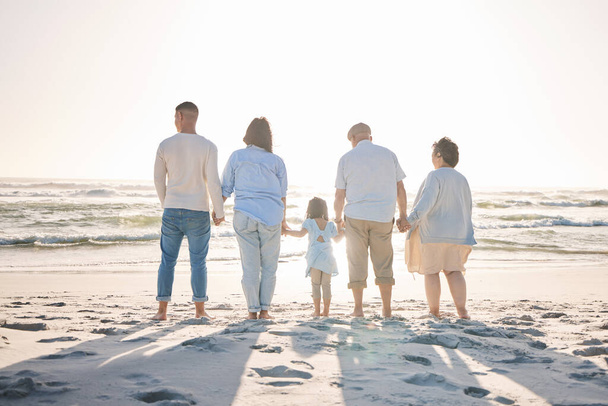 Summer, relax and holding hands with big family on beach for vacation, bonding and love. Freedom, care and travel with group of people walking at seaside holiday for generations, happiness and mockup. - Photo, Image