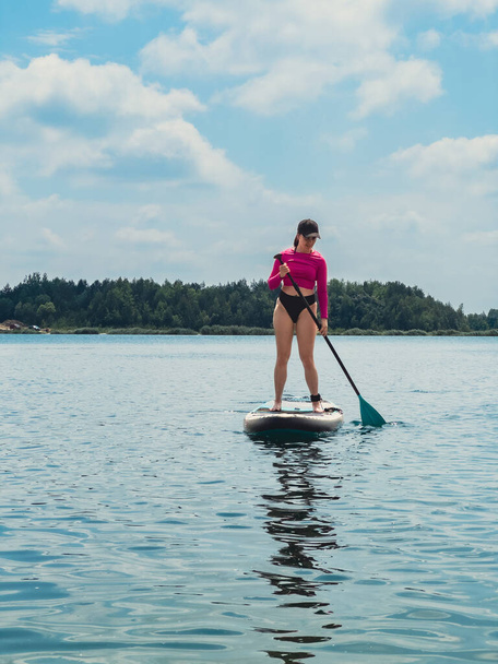 belle femme debout sur supboard garder l'équilibre froid sur les activités de l'eau du lac - Photo, image