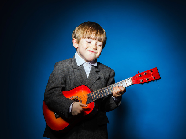 Red-haired preschooler boy with ukalele, music concept - Fotó, kép