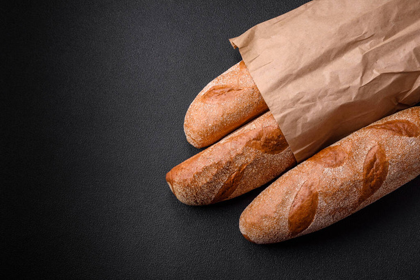 French baguette bread on a dark textured concrete background. Making delicious bruschetta at home - Photo, Image