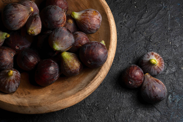 Fresh ripe figs of the Bordissot Black Rimada variety in a wooden plate on a black background - Photo, Image