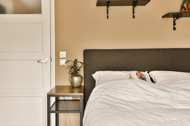 un dormitorio con una cama y estantes en la pared al lado de la cama es una puerta abierta que conduce a otra habitación - Foto, imagen