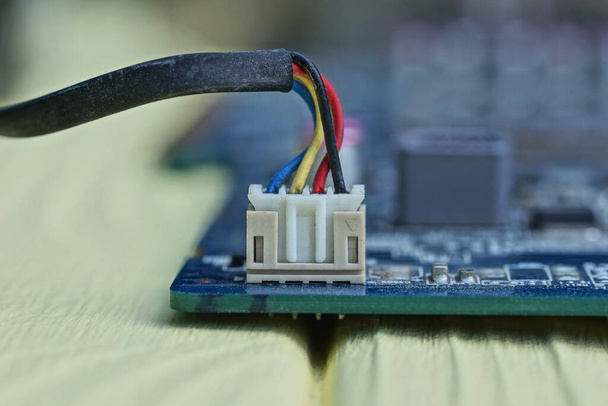 ein Satz elektrischer Drähte in einer Steckdose auf einem Mikrokreis eines elektronischen Geräts auf einem gelben Tisch - Foto, Bild